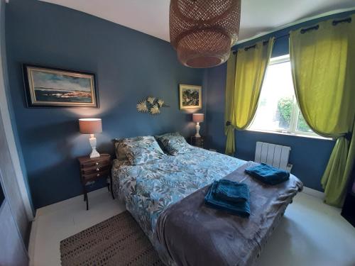 une chambre bleue avec un lit et une fenêtre dans l'établissement Maison Chaleureuse Bord de Mer, à Primelin