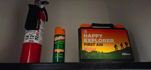 a shelf with a happy explorer first aid book and a fire extinguisher at Breathe Easy Here in Buda 3bd 2ba Home in Buda