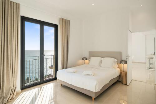 a bedroom with a bed and a large window at Hôtel Le Roquebrune in Roquebrune-Cap-Martin