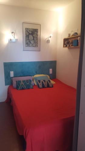 une chambre avec un lit rouge avec deux oreillers dans l'établissement T2 face et proche mer et gare, à La Celle-sous-Gouzon