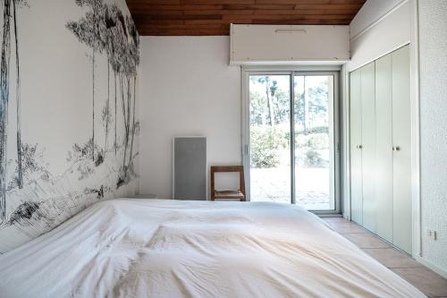 une chambre avec un grand lit blanc et une fenêtre dans l'établissement Villa Lou Lan, à Biscarrosse