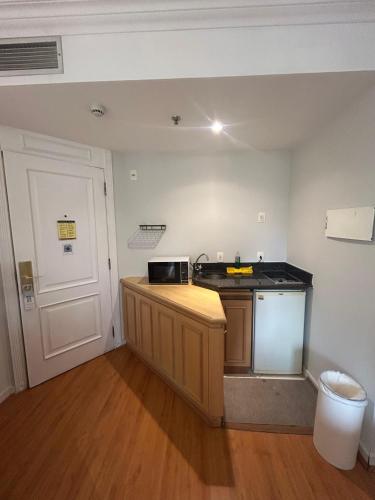 a small kitchen with a counter top and a door at Hotel Pamplona Jardins Univer com garagem 2402 in Sao Paulo