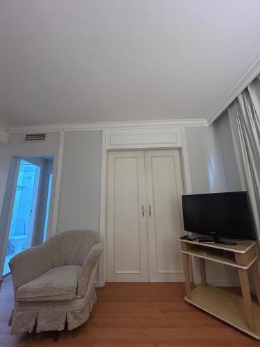 a living room with a chair and a television at Hotel Pamplona Jardins Univer com garagem 2402 in Sao Paulo