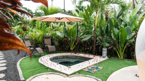 a pool with an umbrella in a yard with grass at Arenal Nest in San Francisco