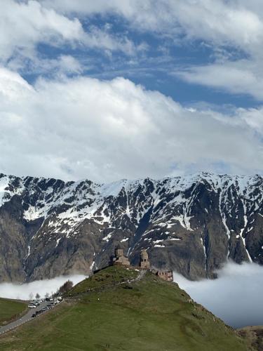 a castle on top of a mountain with snow covered mountains at Devdaraki Apartments N 113 in Stepantsminda