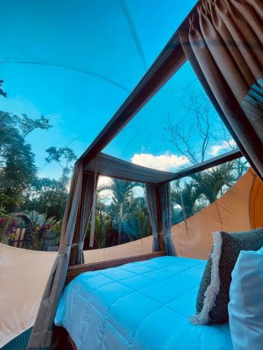 a bed in a tent with a large window at Arenal Nest in San Francisco