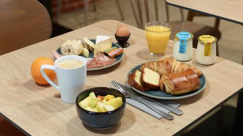a table with two plates of breakfast foods and drinks at Campanile NATURE Les Ulis in Les Ulis
