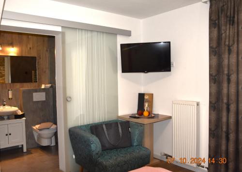 a living room with a chair and a television on the wall at Landhotel Anna in Sankt Martin am Tennengebirge