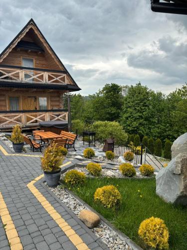 a building with a picnic table and benches in a garden at DOMKI NA WIERCHU in Biały Dunajec