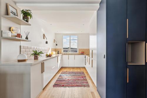 - une cuisine avec des placards blancs et un tapis au sol dans l'établissement Appartement vue sur TOUT Paris !, à Boulogne-Billancourt