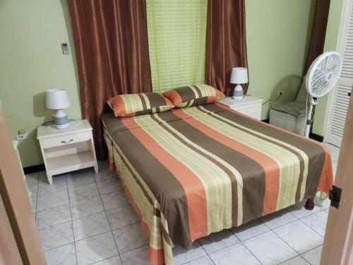 a bedroom with a bed and two night stands with lamps at Finest Accommodation Renfrew Place 4-12 Renfrew Rd 2 bedroom 2 bat Apt # 15 New Kinston Jamaica in Kingston