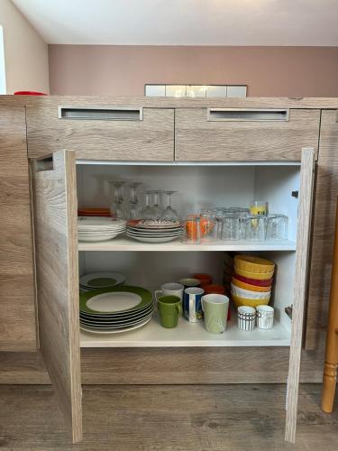 une armoire remplie de assiettes, de bols et de vaisselle dans l'établissement Confort et ressourcement au calme et au vert, à Renaison