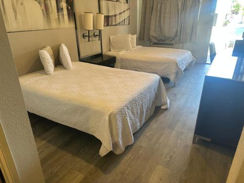 a hotel room with two beds and a mirror at GO2 Inn & Suites by Relianse - El Paso in El Paso