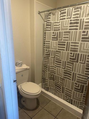 a bathroom with a toilet and a shower curtain at GO2 Inn & Suites by Relianse - El Paso in El Paso
