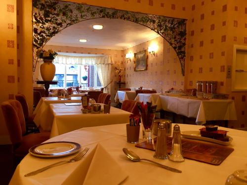a restaurant with tables with white tablecloths and utensils at Bromwell Court in Llandudno
