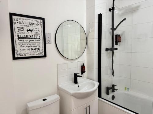 a white bathroom with a sink and a mirror at City Centre Embankment Apartments Superb Location in Cardiff