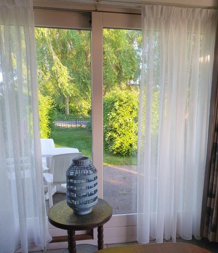 a vase sitting on a table in front of a window at Vakantiehuisje Het Melkmeisje in Kaatsheuvel
