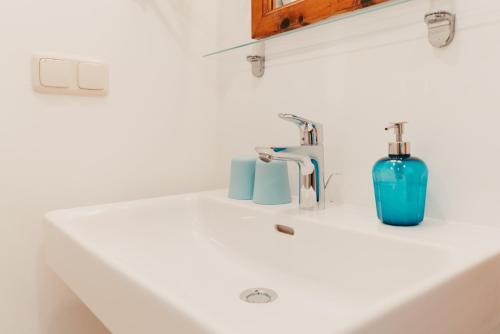 a white bathroom sink with a blue vase on it at Strandcafé Hideaways Altaussee in Altaussee