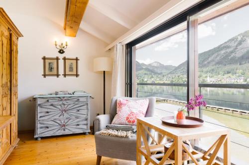 a living room with a table and a chair and a large window at Strandcafé Hideaways Altaussee in Altaussee