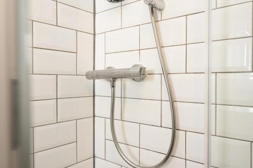 a shower with a hose attached to a white tiled wall at Cottage nr BikeParkWales/Brecon Beacons/PenYFan in Merthyr Tydfil