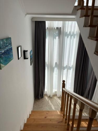 a staircase leading to a large window with curtains at OK Sakhli VIP in Shekvetili