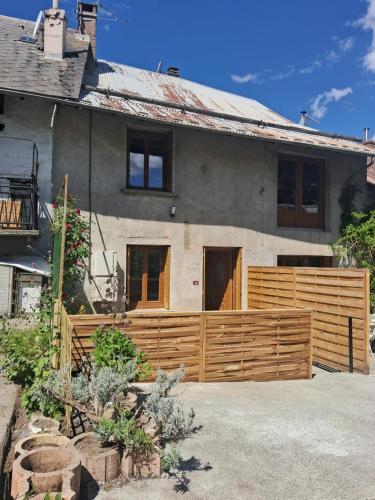 a house with a wooden fence in front of it at Le "46" jusqu'à 6 personnes in Crots