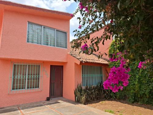 a pink house with pink flowers in front of it at Confortables habitaciones en zona residencial de Vista Bella, Morelia Michoacan in Morelia