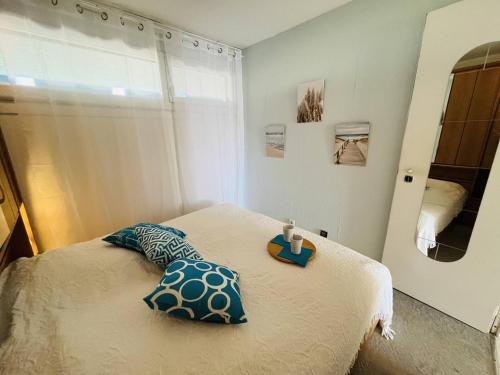 une chambre avec un lit avec des oreillers bleus et un miroir dans l'établissement Deux pièces CAP D'AGDE NATURISME CN030-209, au Cap d'Agde