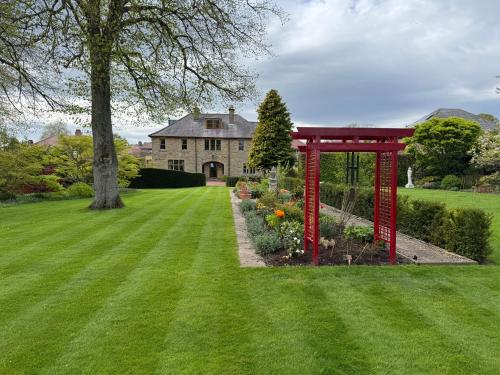 a garden with a red gazebo in front of a house at West Acre House in Alnwick