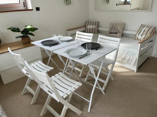 une table de salle à manger blanche avec des chaises blanches et un lit dans l'établissement Joli studio - 1ere ligne- Front de mer Royan, à Royan