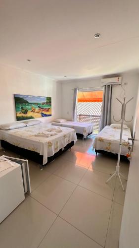 a bedroom with two beds and a painting on the wall at Pousada Vieira in Paraty