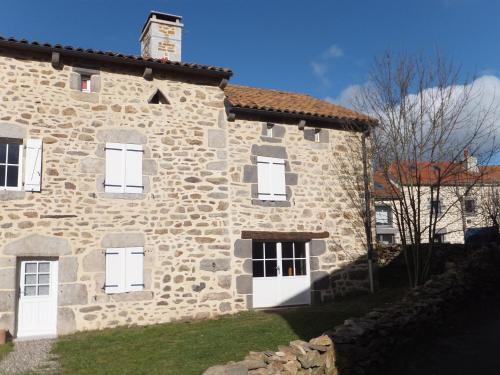Casa de piedra con ventanas blancas y pared de piedra en Le Relais de Garabit, en Anglards-de-Saint-Flour