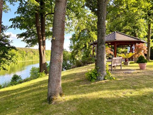 a gazebo with a bench next to a lake at Ruhe Oase Steinhöfel - Balkon, Naturblick, Design-Maisonette-Apartment - nahe Fürstenwalde-Spree in Steinhöfel