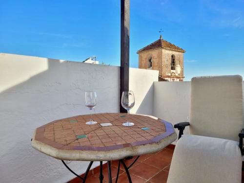 a table and two wine glasses on a balcony at Tradicional casa con impresionantes vistas in Gaucín