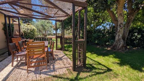 a wooden pergola with a table and chairs in a yard at Podere Isabella in San Vincenzo