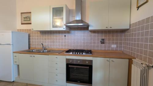 a kitchen with white cabinets and a sink and a refrigerator at Podere Isabella in San Vincenzo