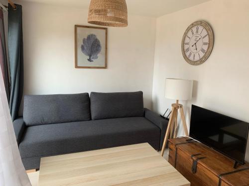 un salon avec un canapé et une horloge au mur dans l'établissement Les Petites Maisons de la Clarté - La Bernique, à Perros-Guirec