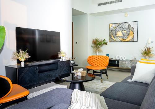 a living room with a large television and orange chairs at 2BR Apartment In Dubai in JVC near Circle mall in Dubai