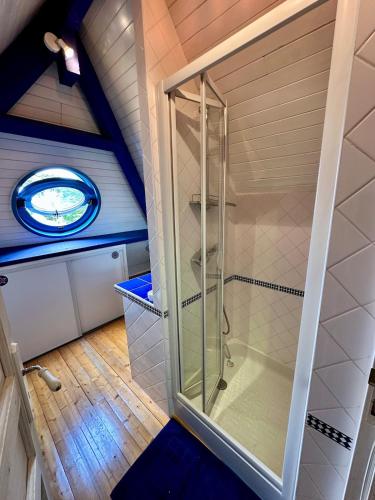 une douche en verre dans une salle de bain mansardée avec une fenêtre dans l'établissement Villa 