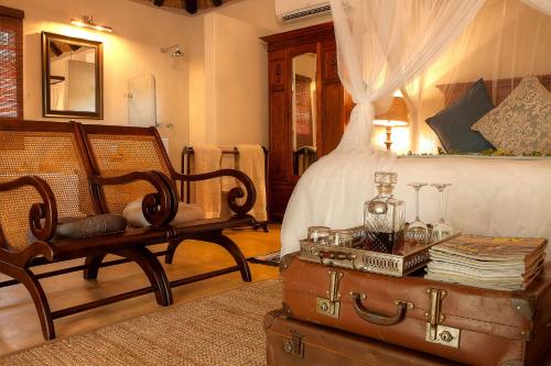 a bedroom with a bed and a chair and a trunk at Mvuradona Safari Lodge in Marloth Park