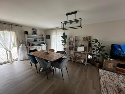 ein Esszimmer mit Tisch und Stühlen und einem Fernseher in der Unterkunft Villa aux oiseaux in Biganos