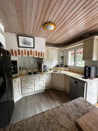 Elle comprend une grande cuisine avec des placards blancs et un plafond en bois. dans l'établissement Villa aux oiseaux, à Biganos