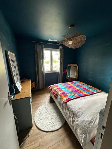 une chambre avec un lit et un mur bleu dans l'établissement Villa aux oiseaux, à Biganos