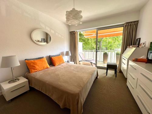 une chambre avec un lit avec des oreillers orange et une fenêtre dans l'établissement Grand T2 direct sur la plage Arcachon Pereire, à Arcachon