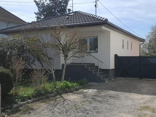 a white house with a black fence and stairs at Maison 5 personnes in Lutterbach