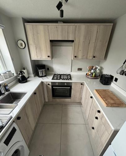 a kitchen with white counter tops and wooden cabinets at Redwing Retreat - Luxury 2 Bed House - Sleeps 6 - Short Walk to Bicester Village Shops, Train Station and Town Centre with Garden and Driveway Parking in Bicester