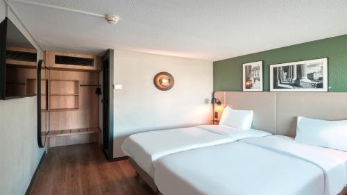 two white beds in a room with green walls at Campanile NATURE - Dreux in Dreux