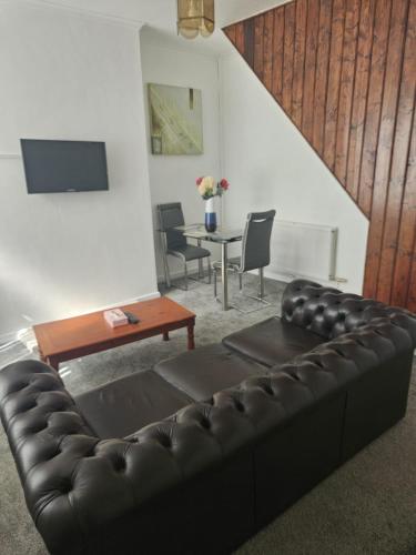 a living room with a black leather couch and a table at Olivetem Comfort House in Bolton
