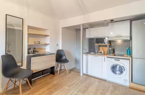 une cuisine avec un lave-linge et deux chaises dans l'établissement Nice - Studette confort sur les toits au cœur du Vieux Nice, à Nice