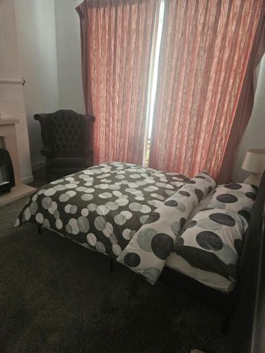 a bed with a black and white comforter and a window at Olivetem Comfort House in Bolton
